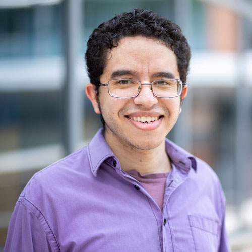 Mason assistant professor Nicholas Rios stands for a headshot photo in front of the Nguyen Engineering building.