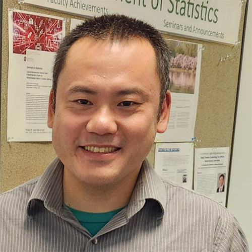 Ray Bai in a gray shirt in front of a research board